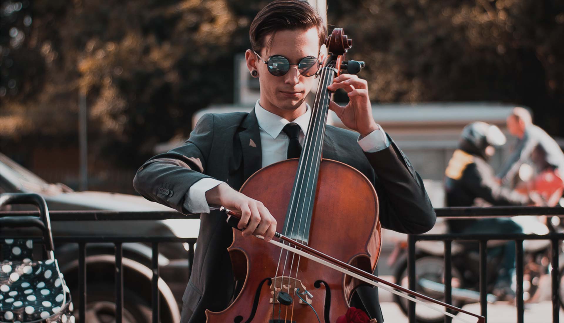 A man in suit and sunglasses playing the cello.