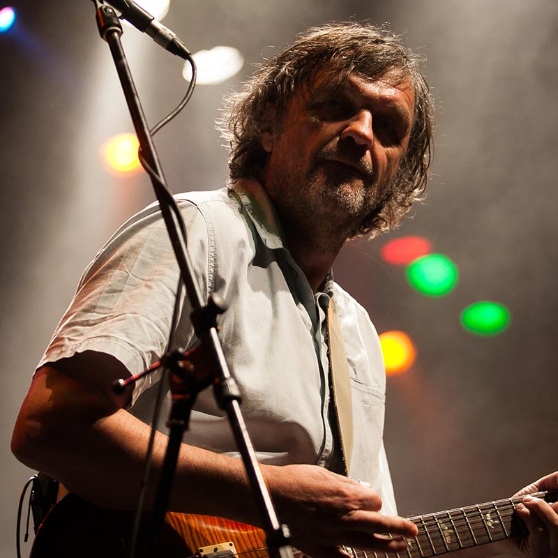 A man with a guitar and microphone on stage.