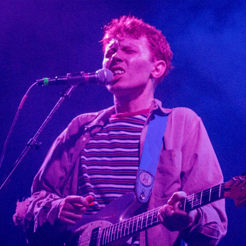 A man with a guitar and microphone on stage.