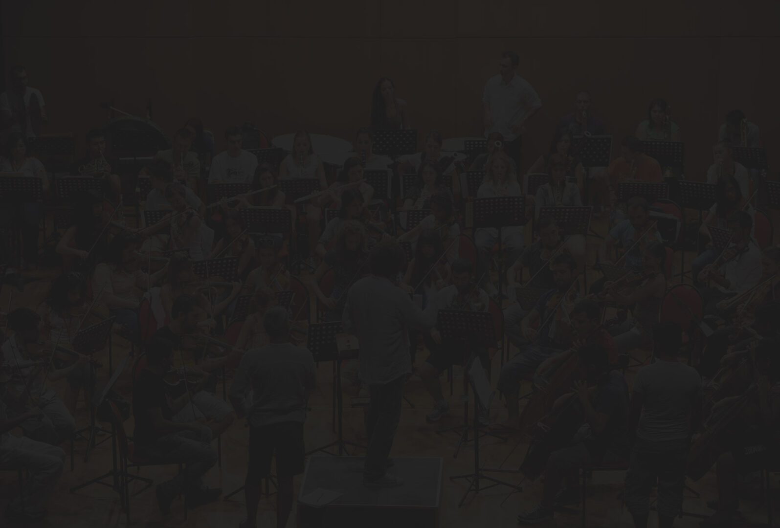 A crowd of people in the dark with one person standing on stage.