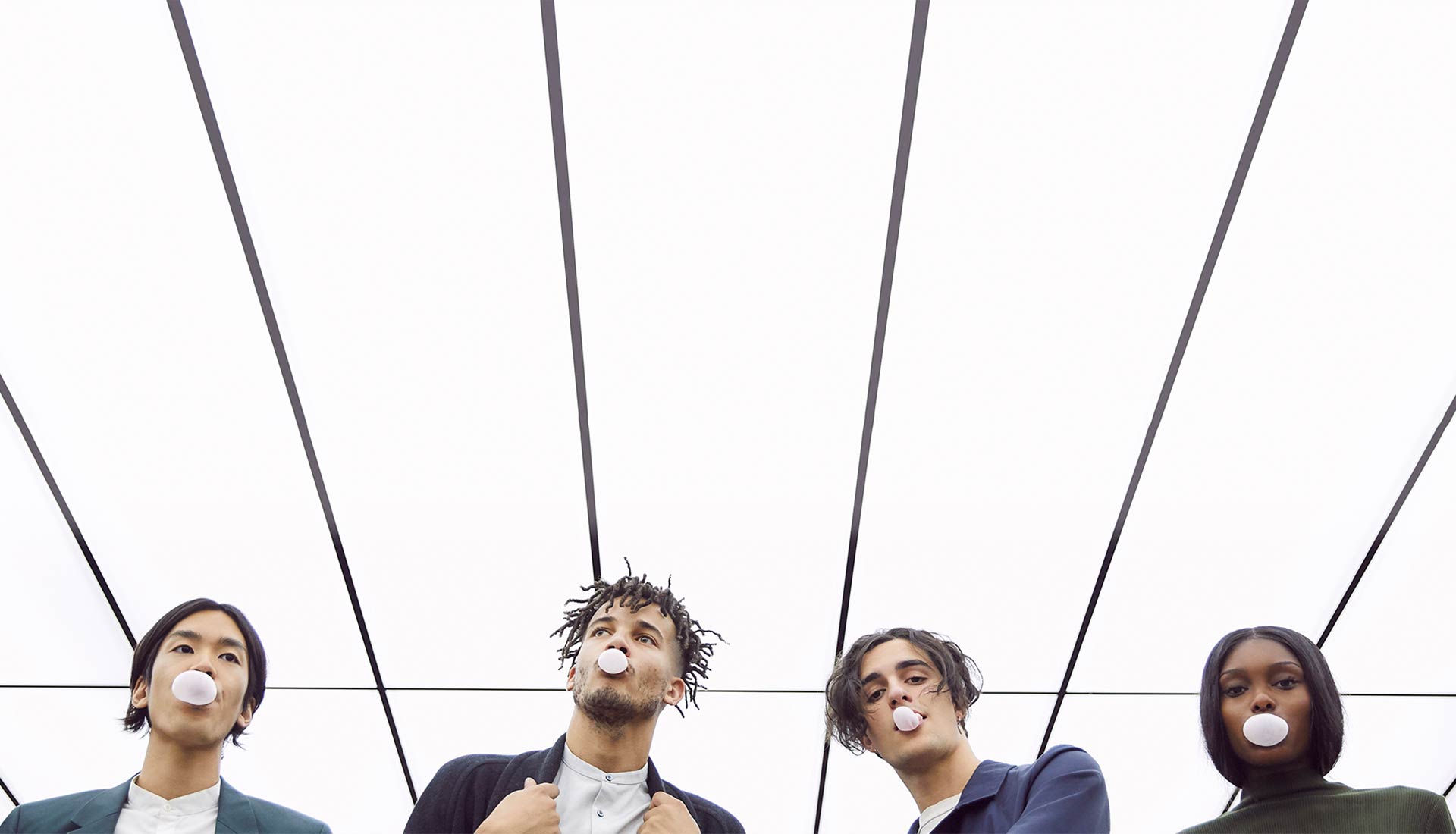 Two men standing under a ceiling with one man smoking.
