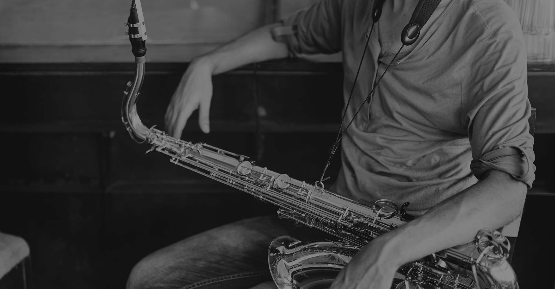 A man playing the saxophone in black and white.
