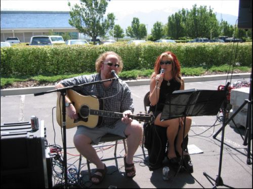 Outdoor duet performance with guitar and microphone.