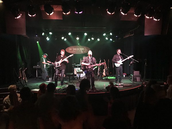 Band performing on stage with green lighting.