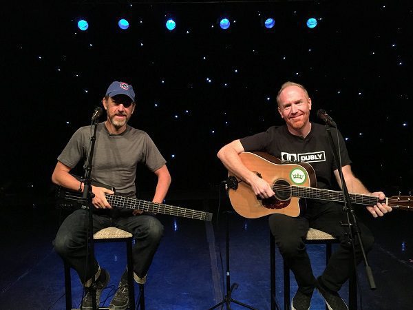 Two musicians playing guitars on stage.