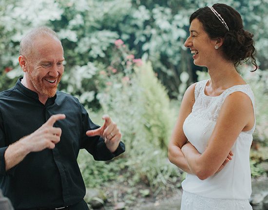 Man and woman smiling and talking outdoors.